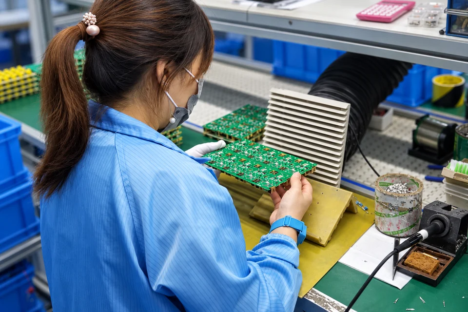 A FAHINT operator handling circuit boards at an electronics assembly bench